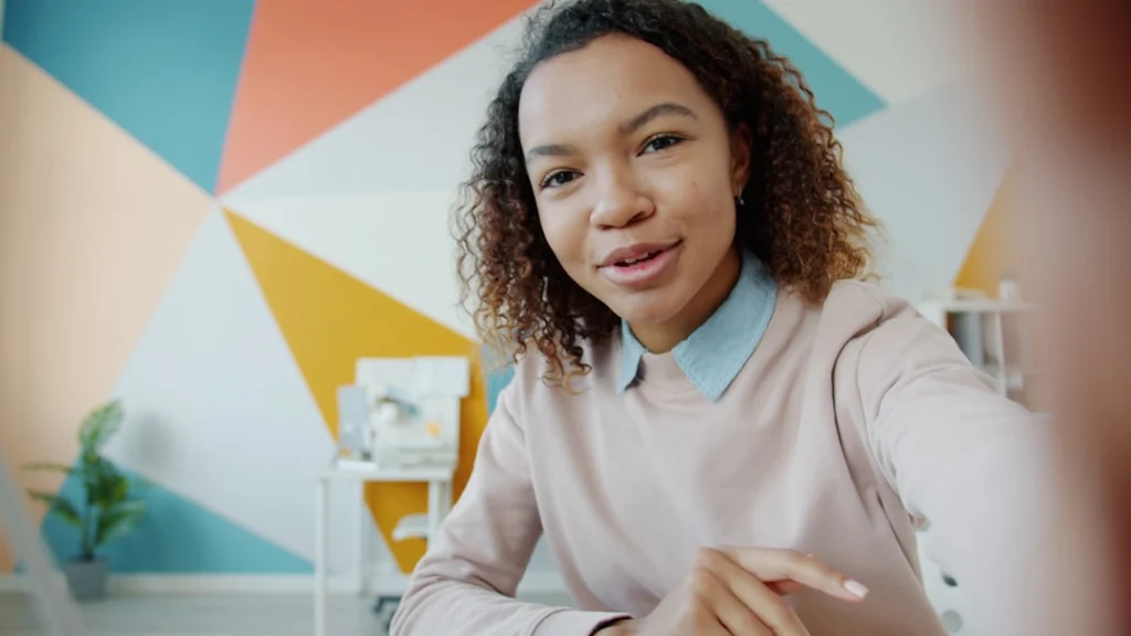 Young woman talking to the camera in a colorful room.